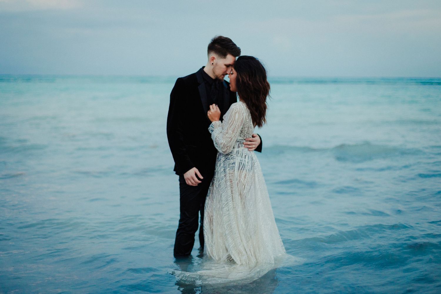 A couple embraces while standing in ocean water during a romantic photoshoot.