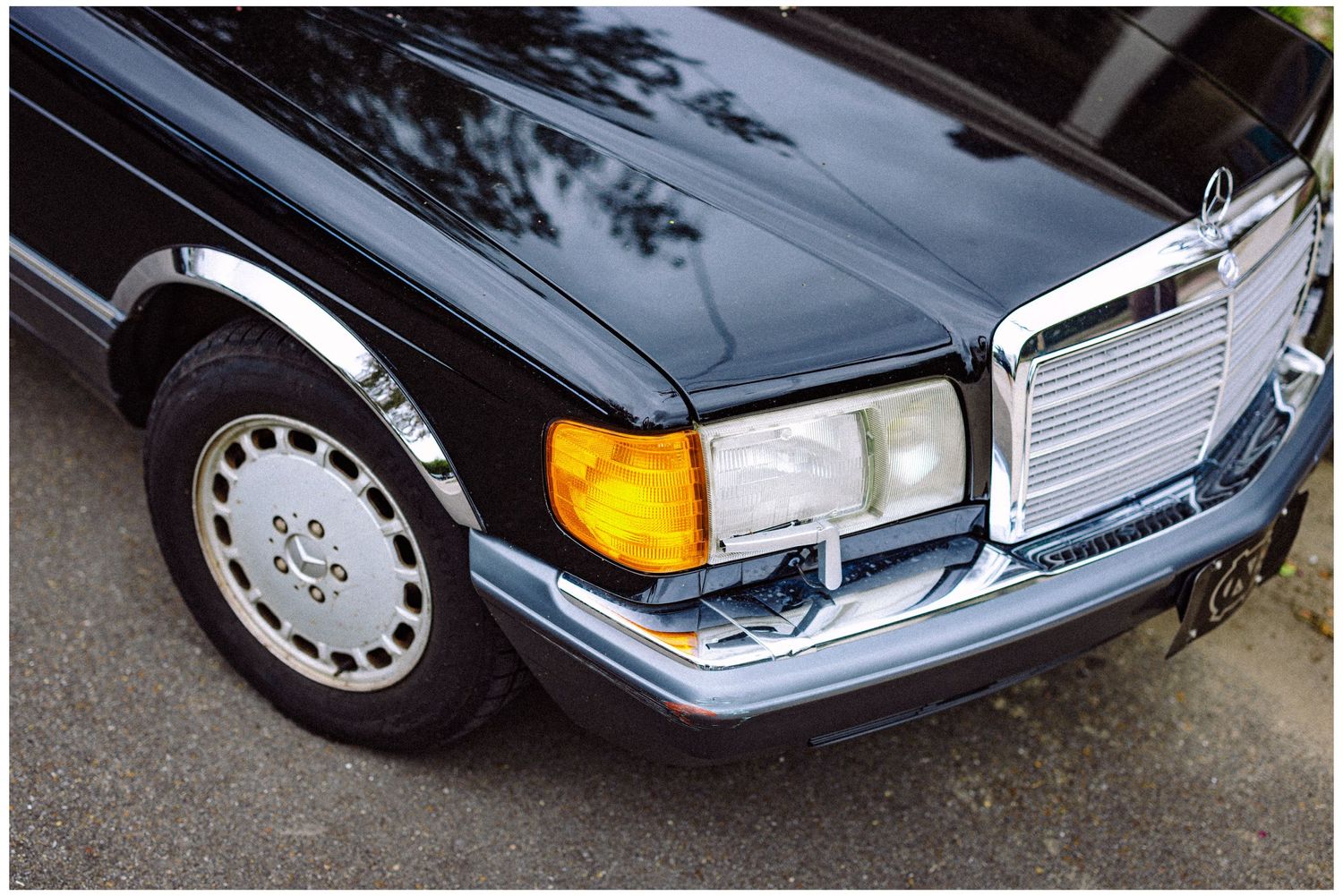 Close-up of classic Mercedes-Benz front end with chrome grille and yellow turn signal.