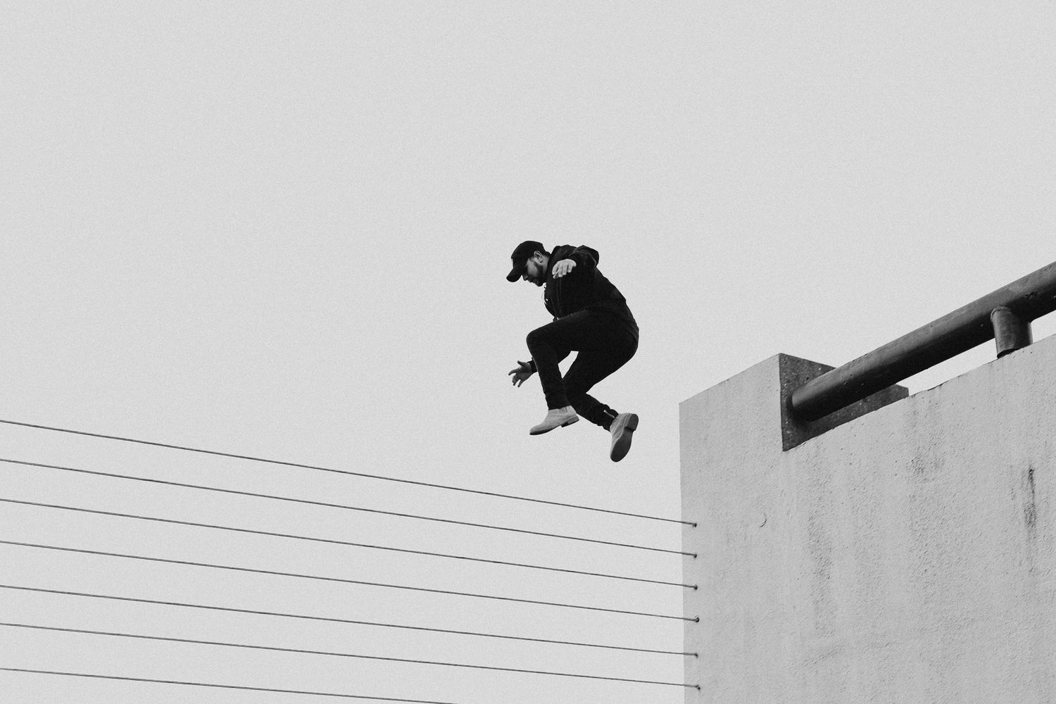Black and white silhouette of skateboarder mid-jump against minimalist background.