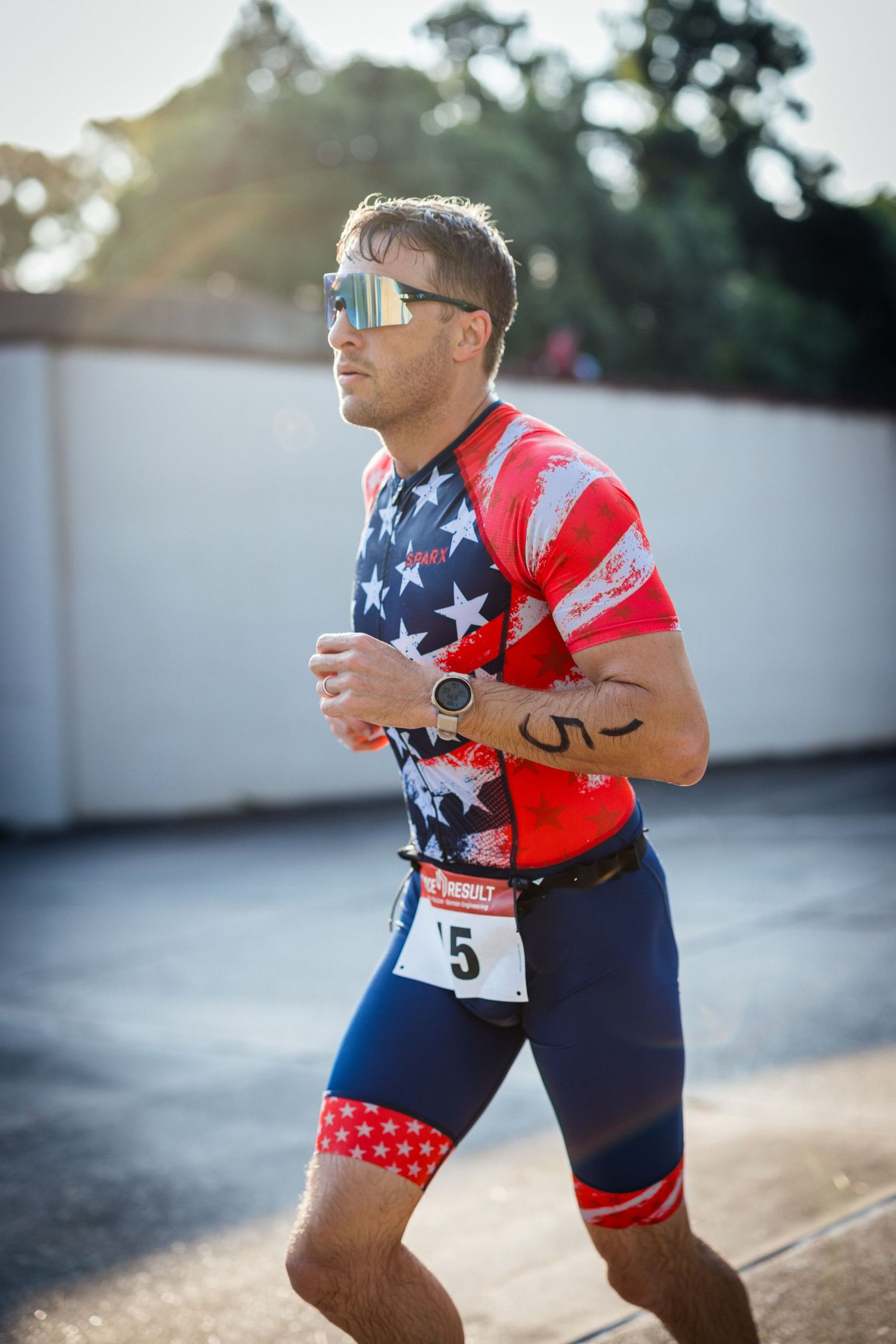 Triathlete in patriotic American flag themed racing kit competes during event.