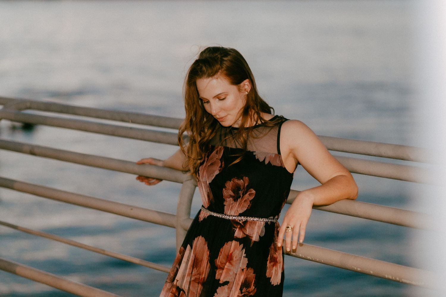 Artistic portrait in warm light with decorative railings and ocean background.