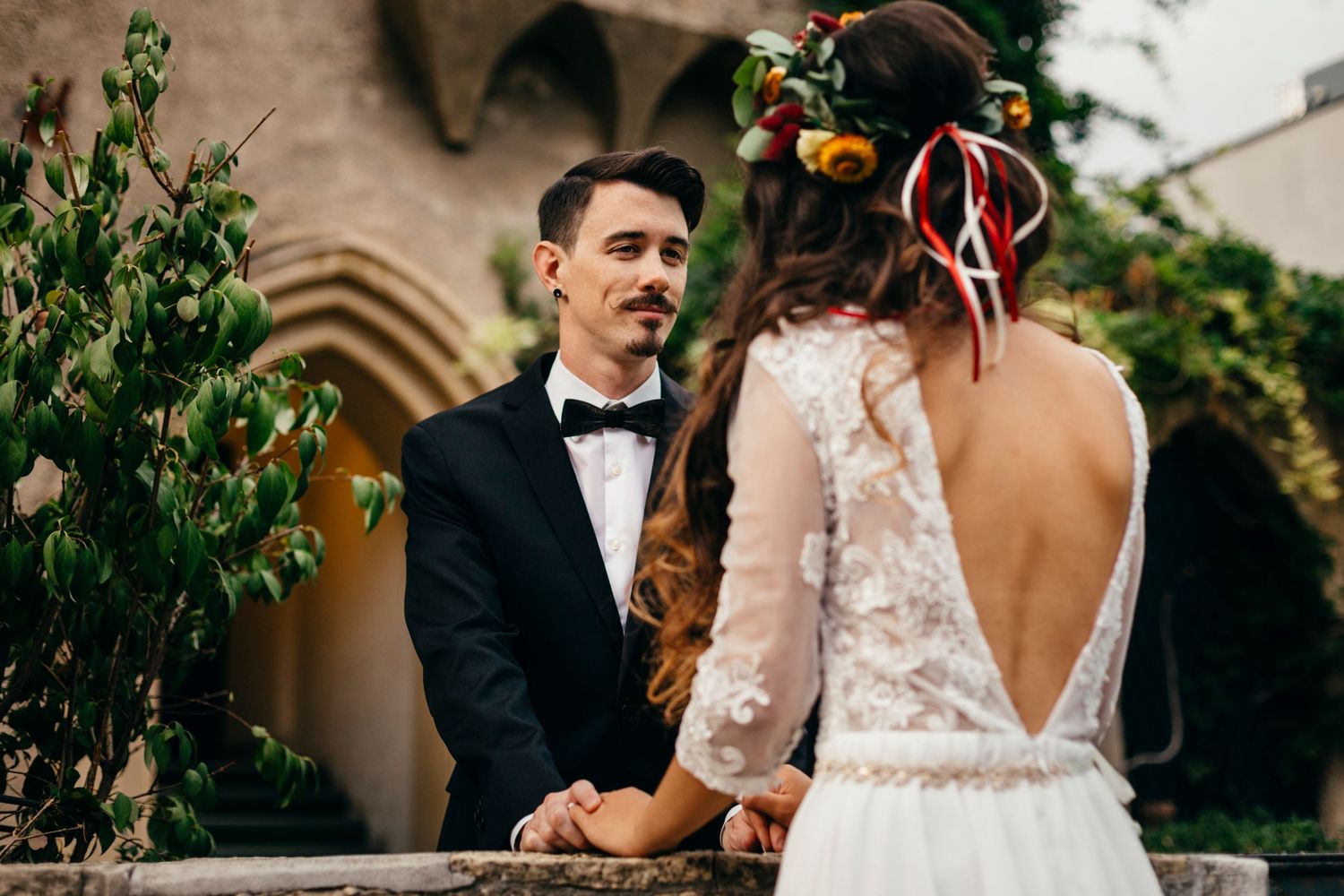 A romantic wedding couple shares an intimate moment in a lush garden setting with elegant formal attire.