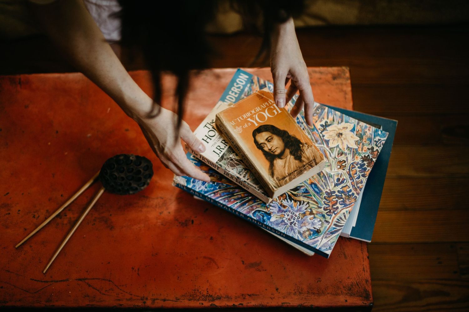 Hands holding vintage photographs and documents on red wooden surface.