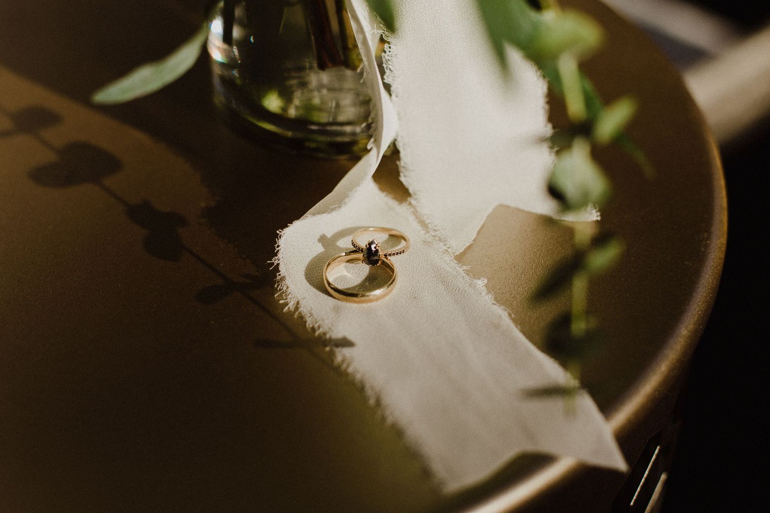 Wedding rings photographed on white feather with artistic lighting.
