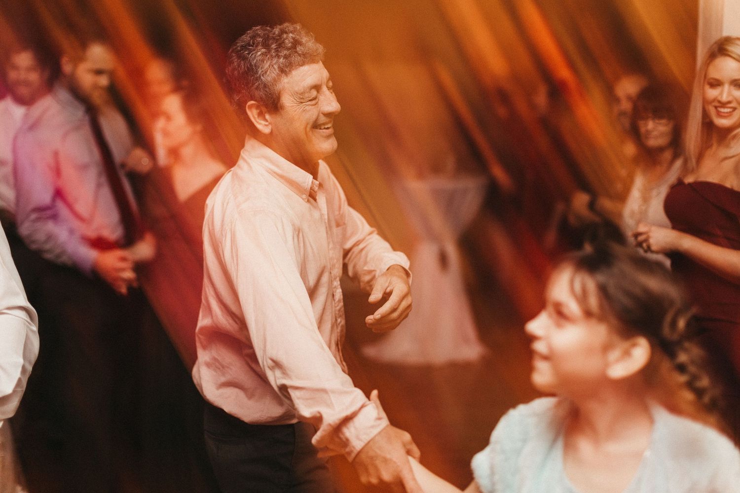 Candid dance floor moment at wedding reception with warm lighting.
