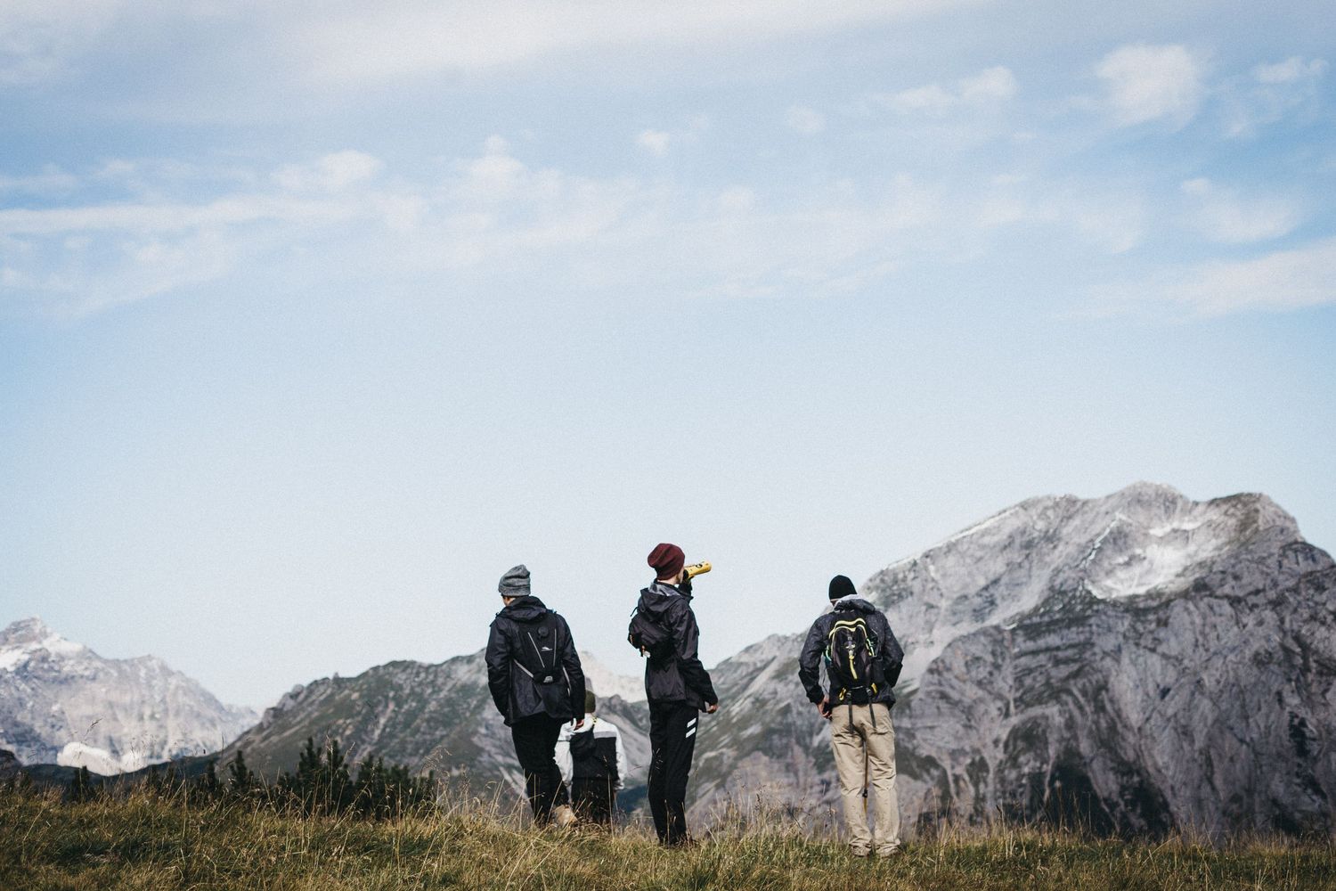 Three hikers admiring a scenic mountain landscape on a cloudy day.