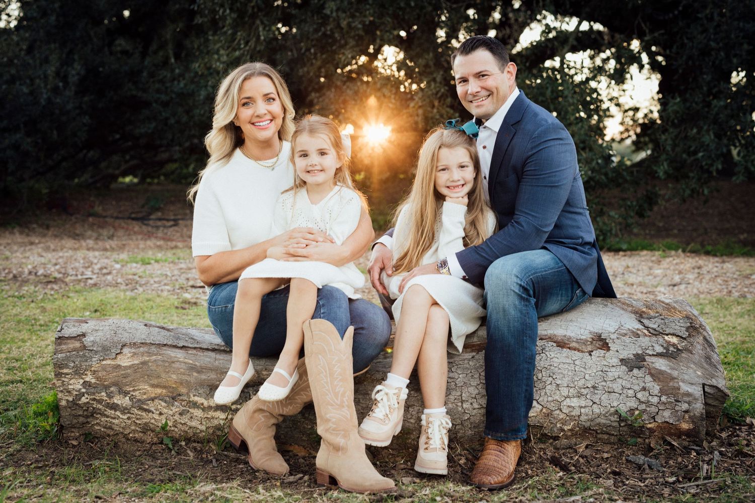 A family sits together on a large rock during sunset.