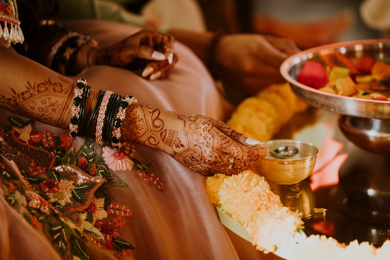 Close-up of intricate henna designs on hands with traditional jewelry.