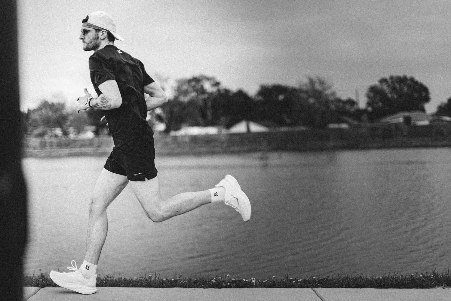Black and white photo of a jogger running along a waterfront path.