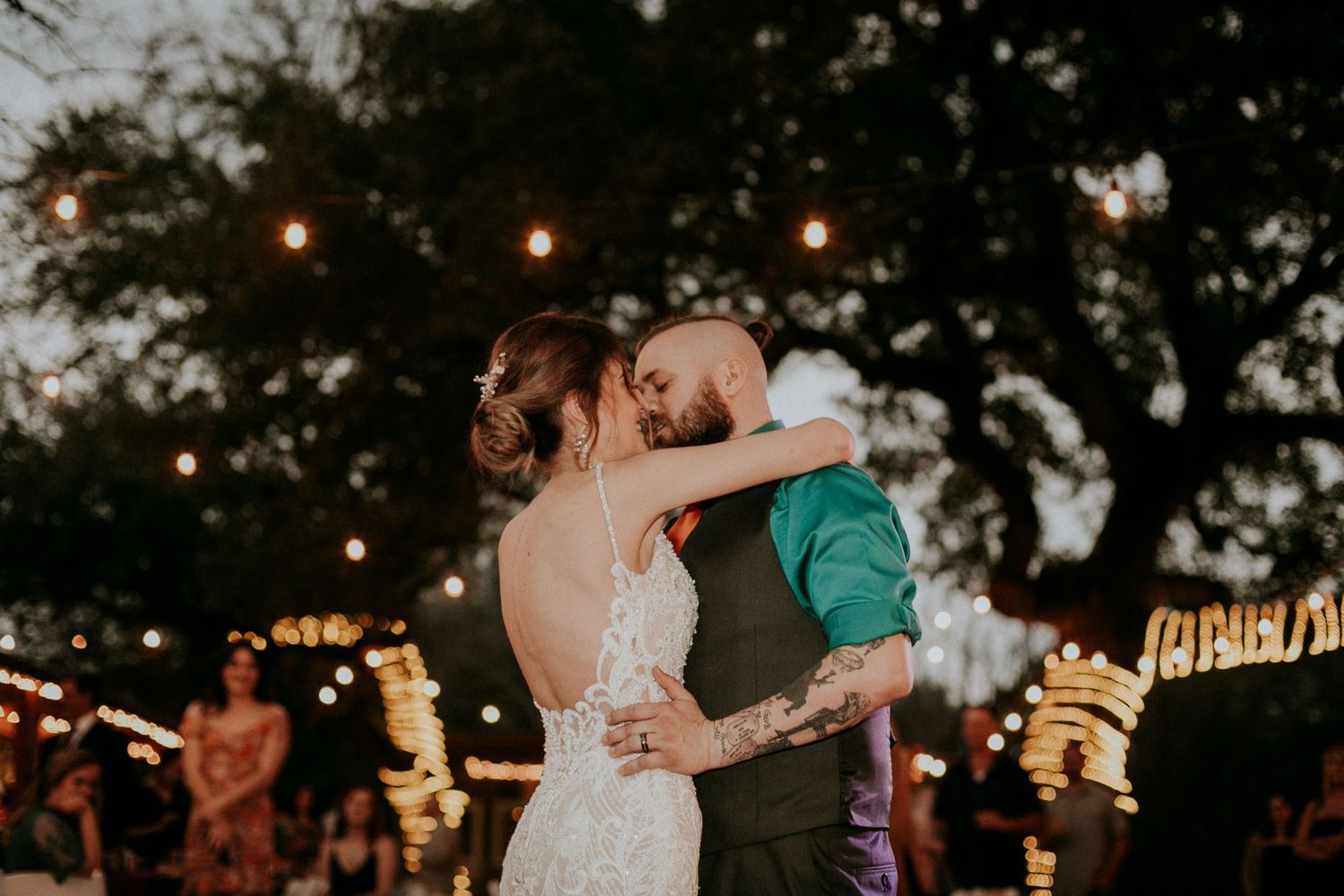 Romantic sunset dance with string lights and trees in background.