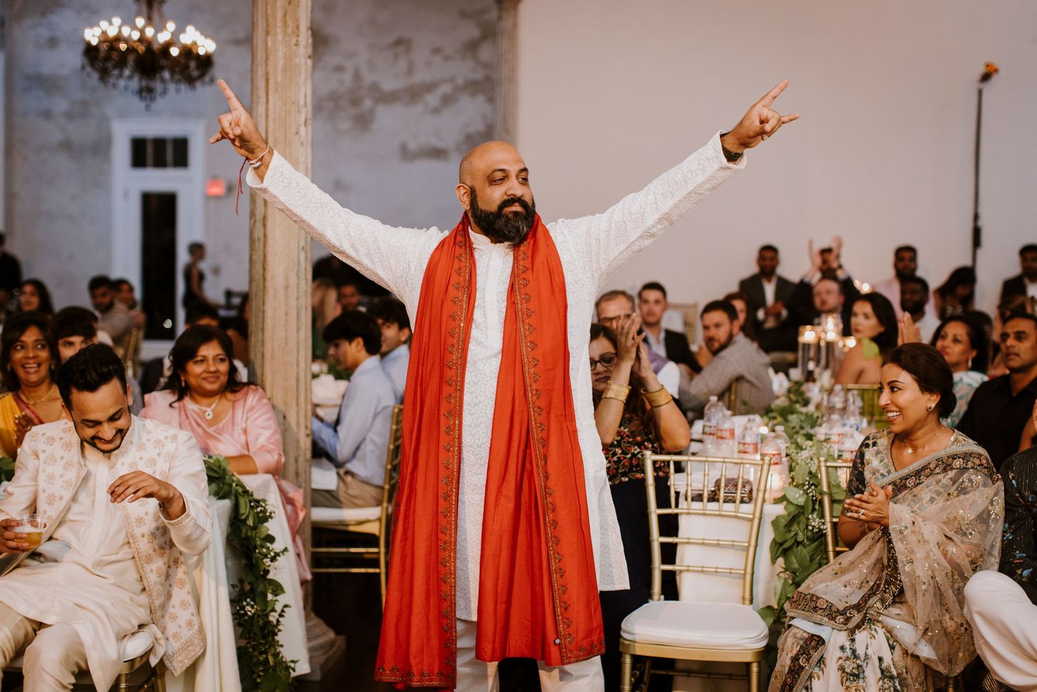 Celebratory moment during an Indian wedding reception with guests in traditional attire.