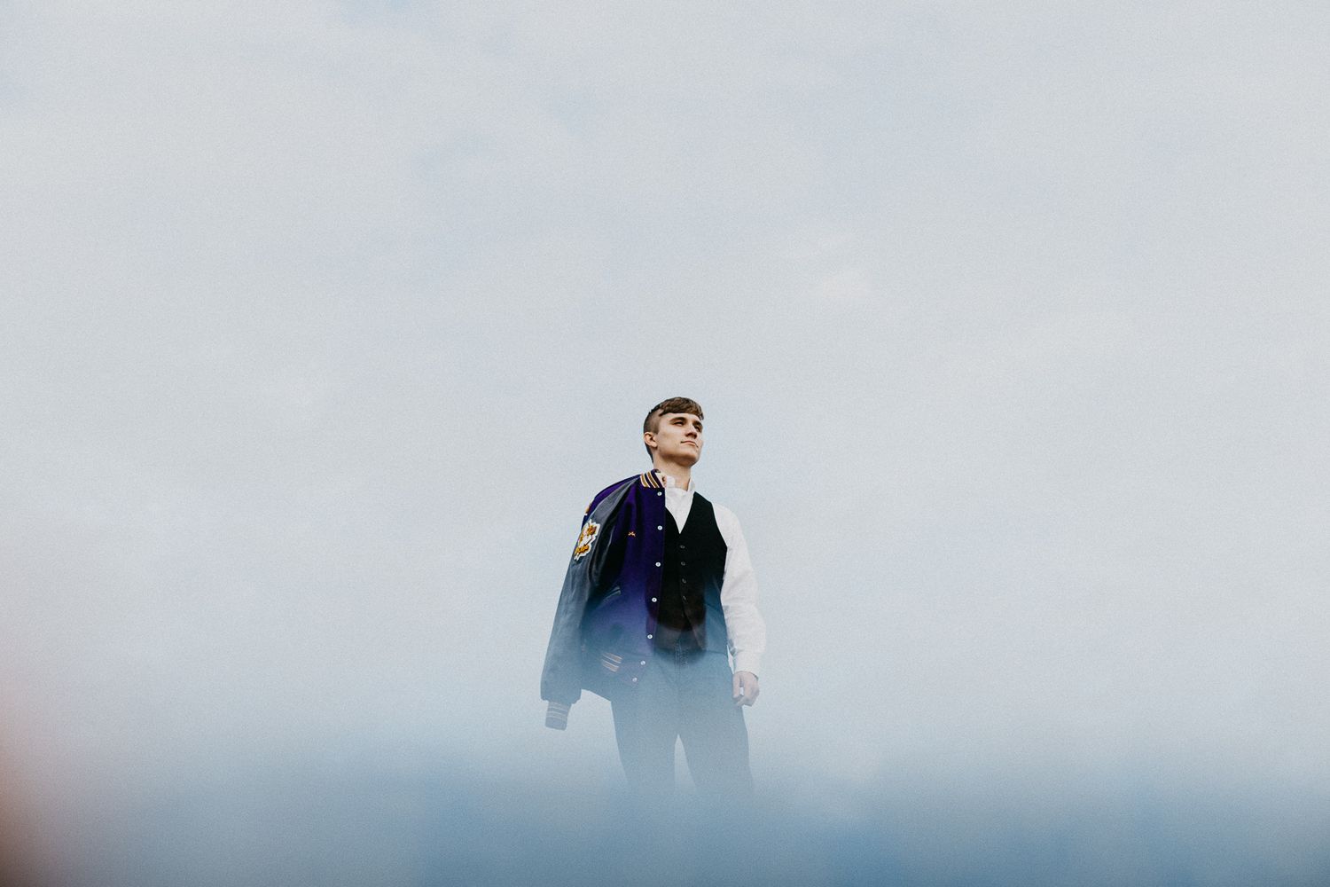 Silhouetted figure stands dramatically against foggy mountain backdrop.