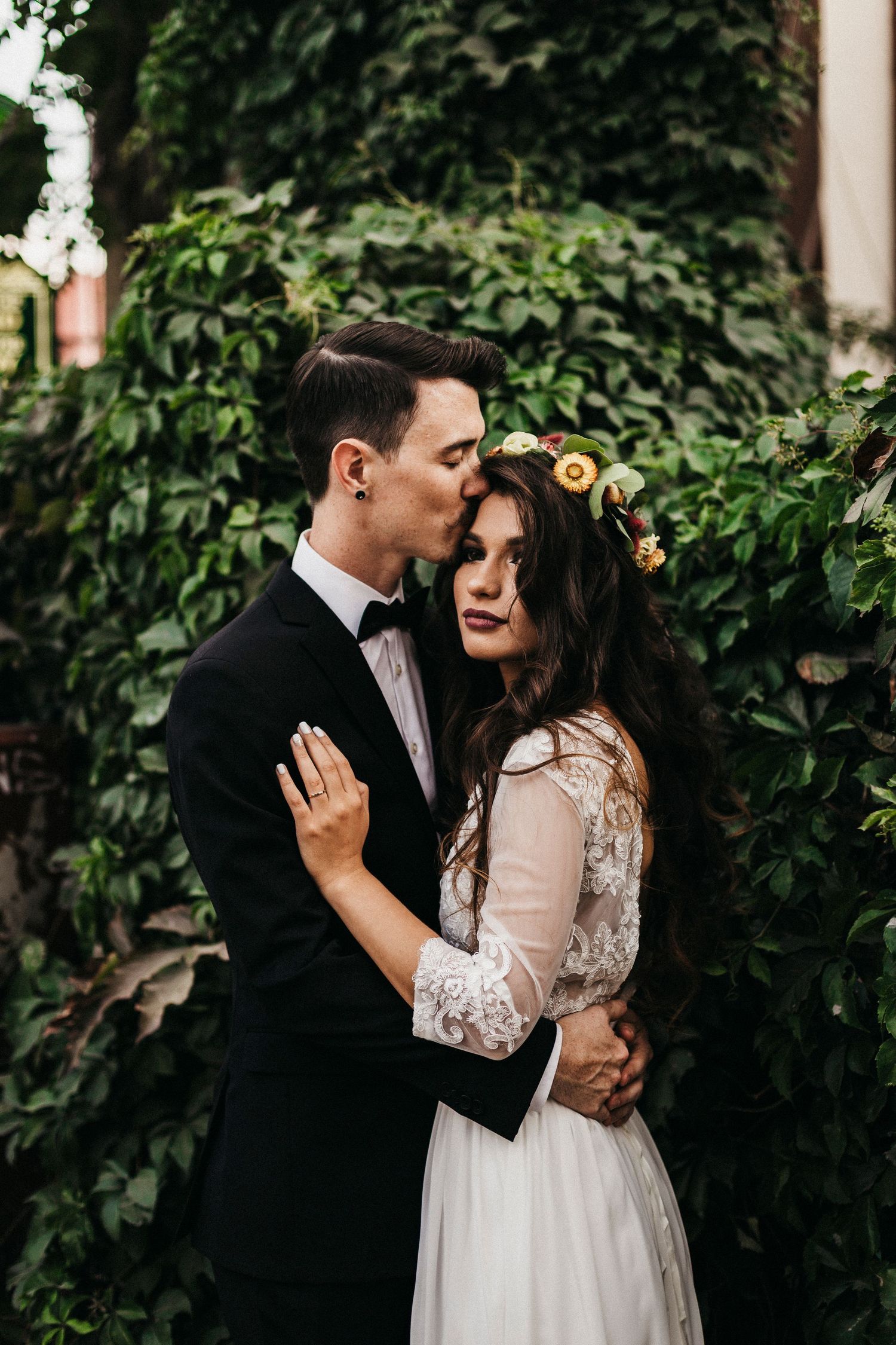 A romantic wedding portrait with a couple embracing against a lush green garden backdrop.
