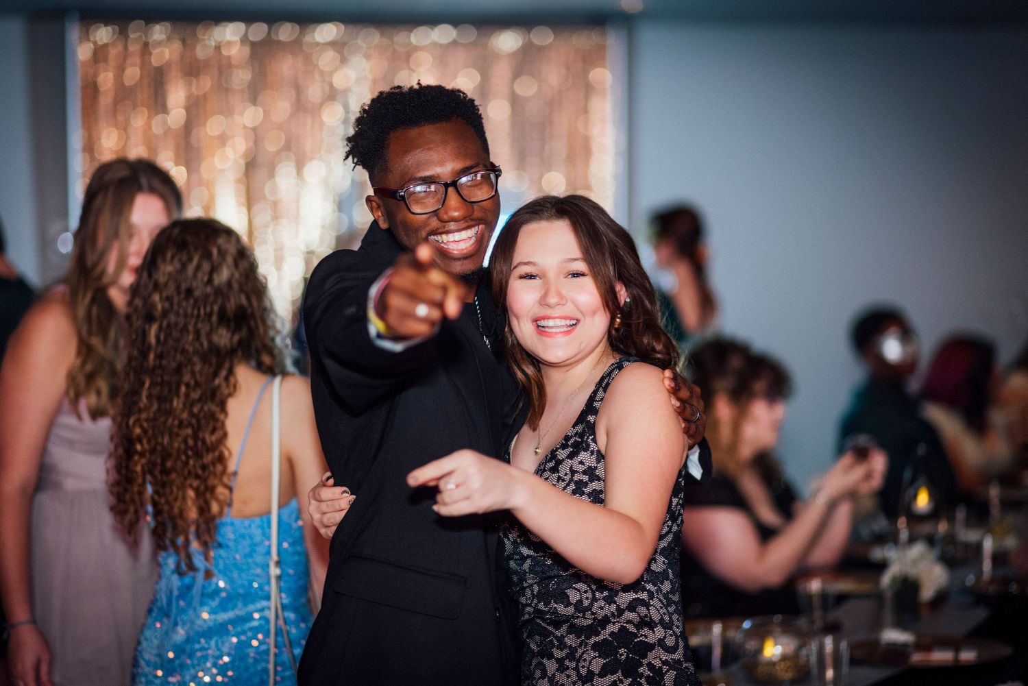 Party guests having fun and pointing at the camera during an indoor celebration.