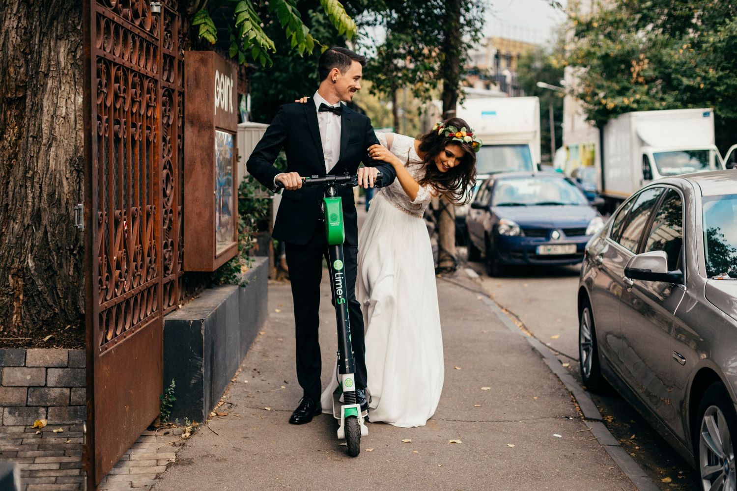 Wedding couple having fun with electric scooter on urban street.