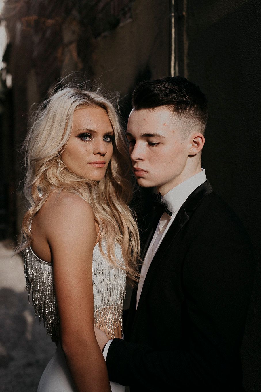 Intimate portrait of couple in formal attire against dark background.