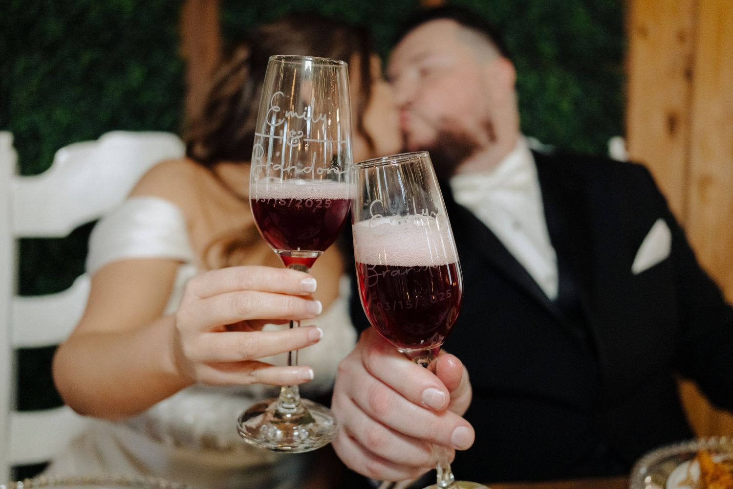 People holding wine glasses in a toast at a formal event with warm lighting and wooden decor.