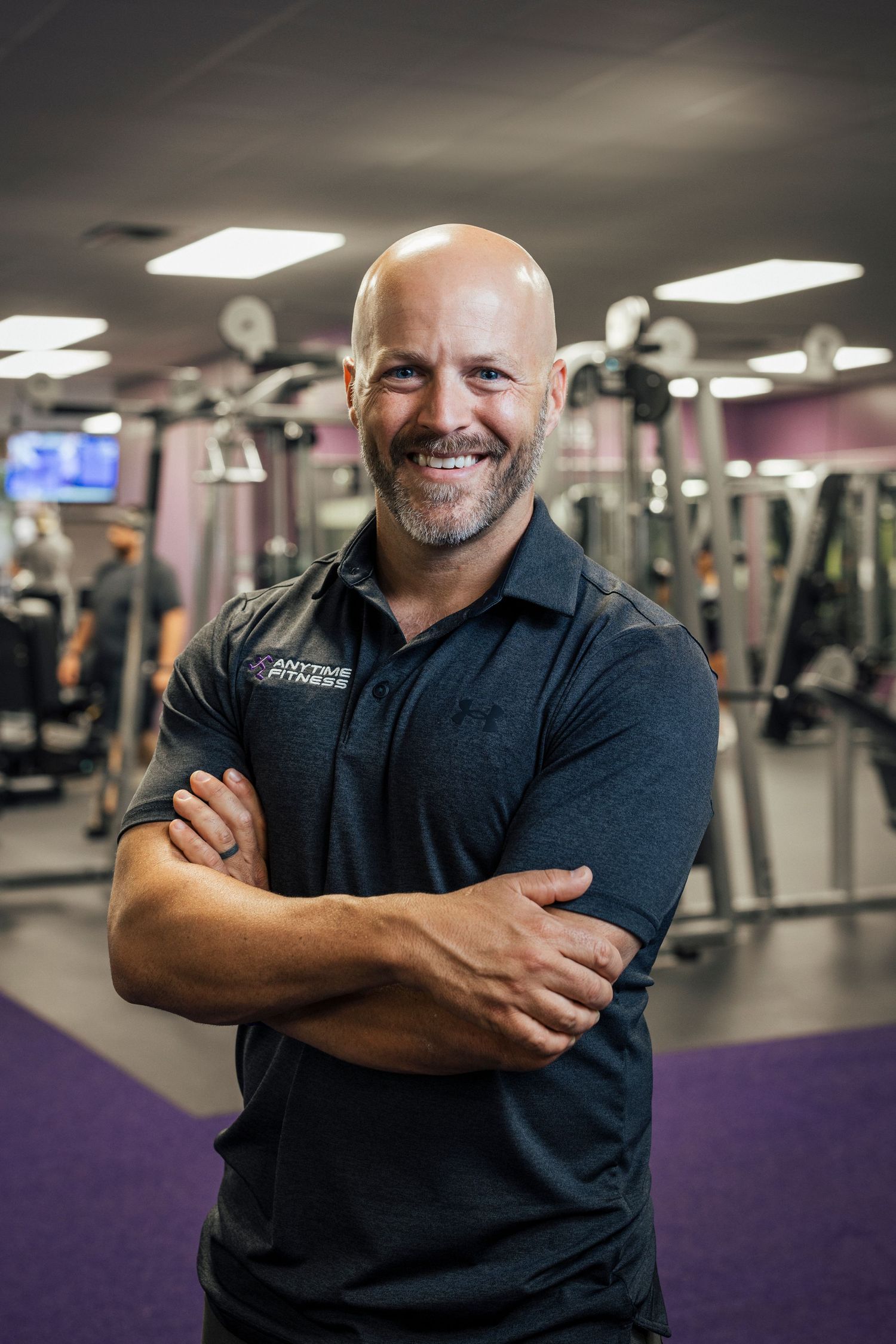 Professional fitness trainer posing in a modern gym setting.
