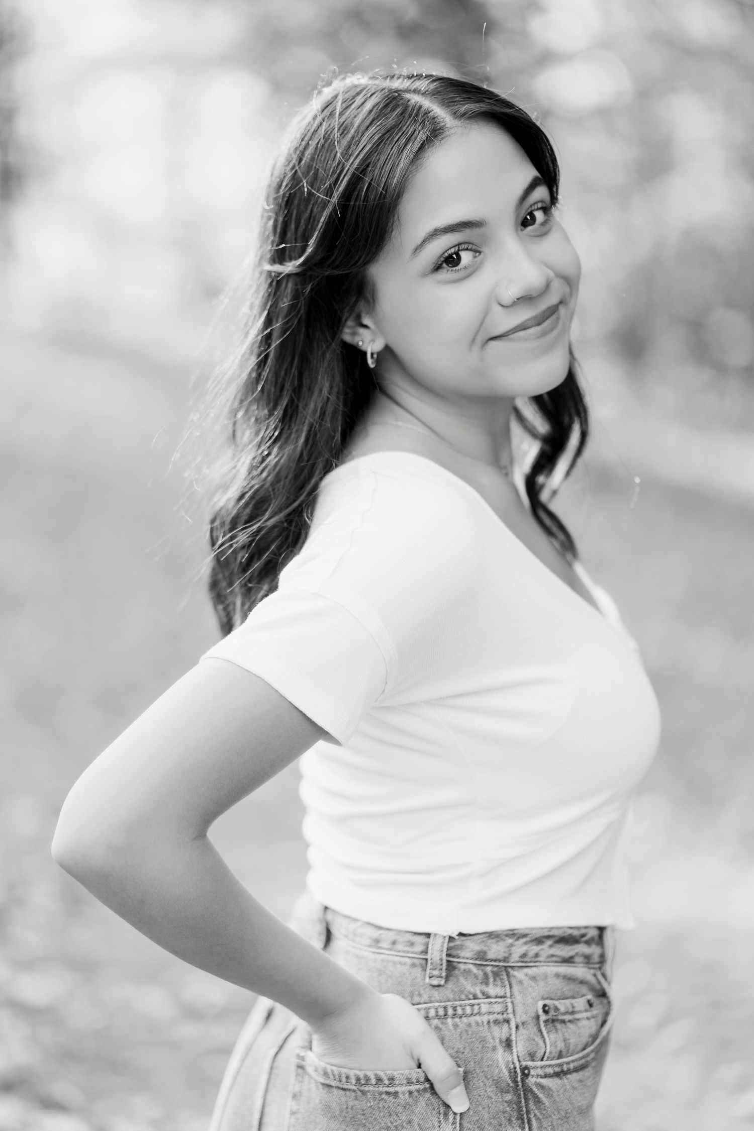 A series of black and white portraits showing someone in a white top and jeans posing outdoors with a dreamy bokeh background.