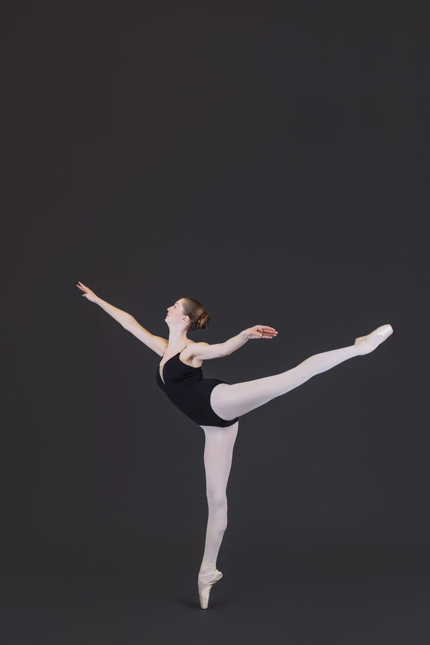 A ballet dancer in black and white attire performs graceful arabesque poses in a series of four connected images.