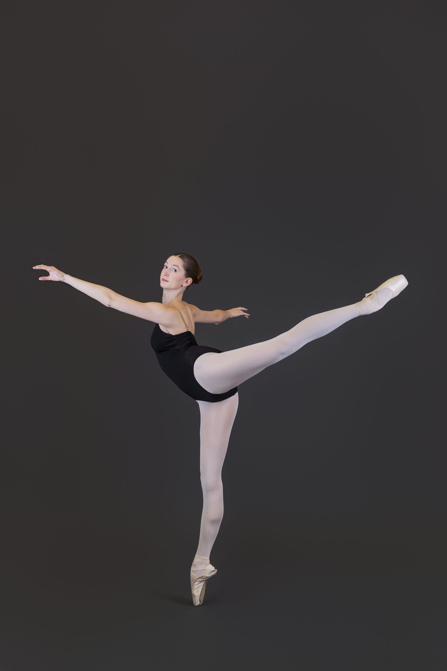 Ballet dancer in pale leotard performs graceful arabesque poses in sequence against dark background.