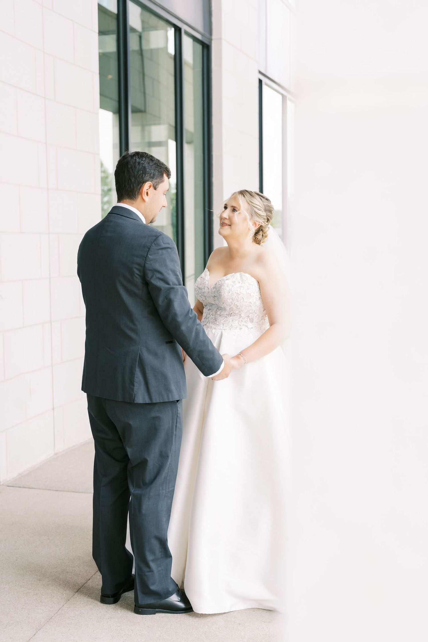 A bride in a white gown and groom in a dark suit share a private moment before their wedding ceremony.