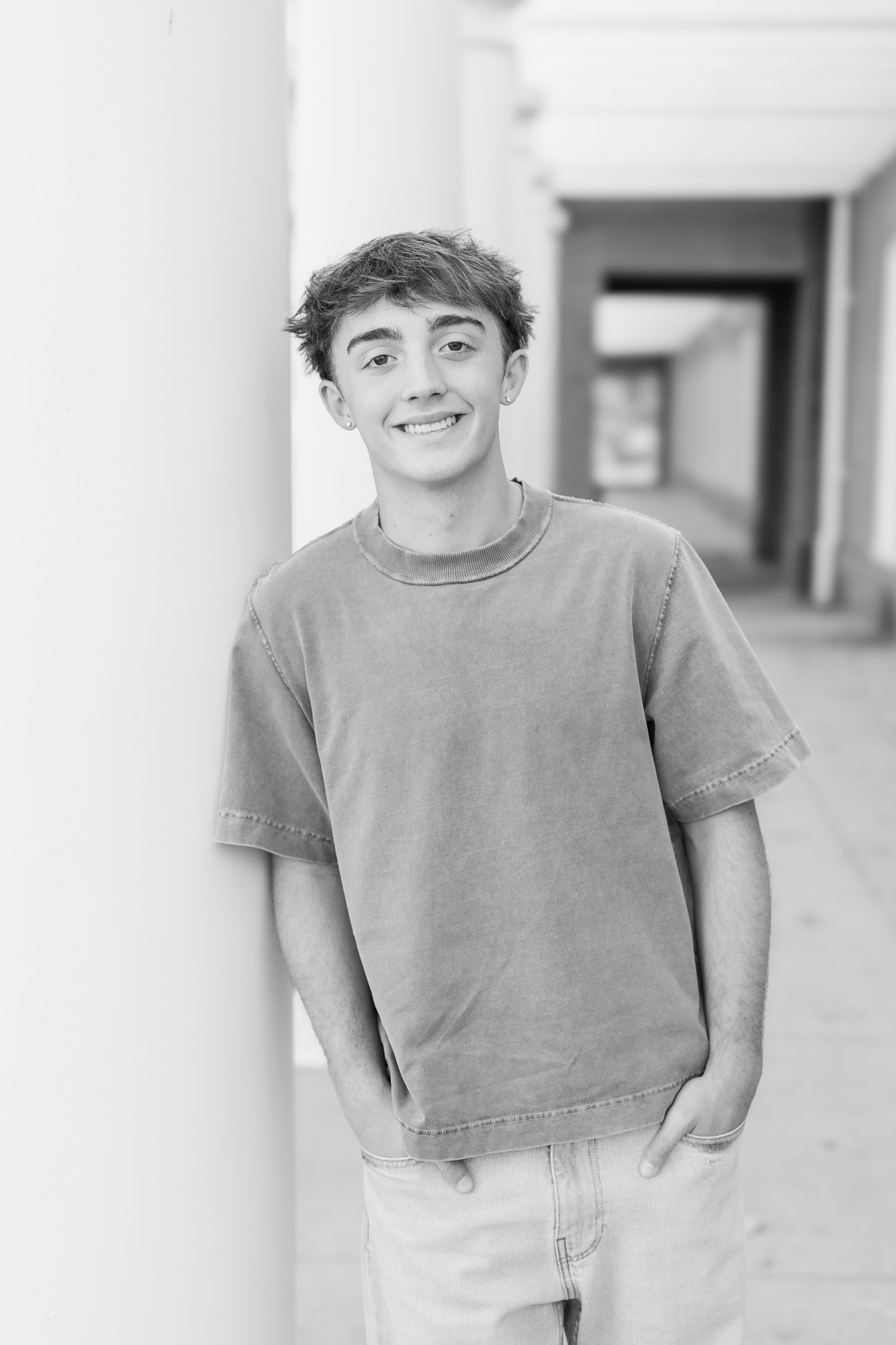 Black and white portrait of someone in a casual gray t-shirt smiling against a light background.