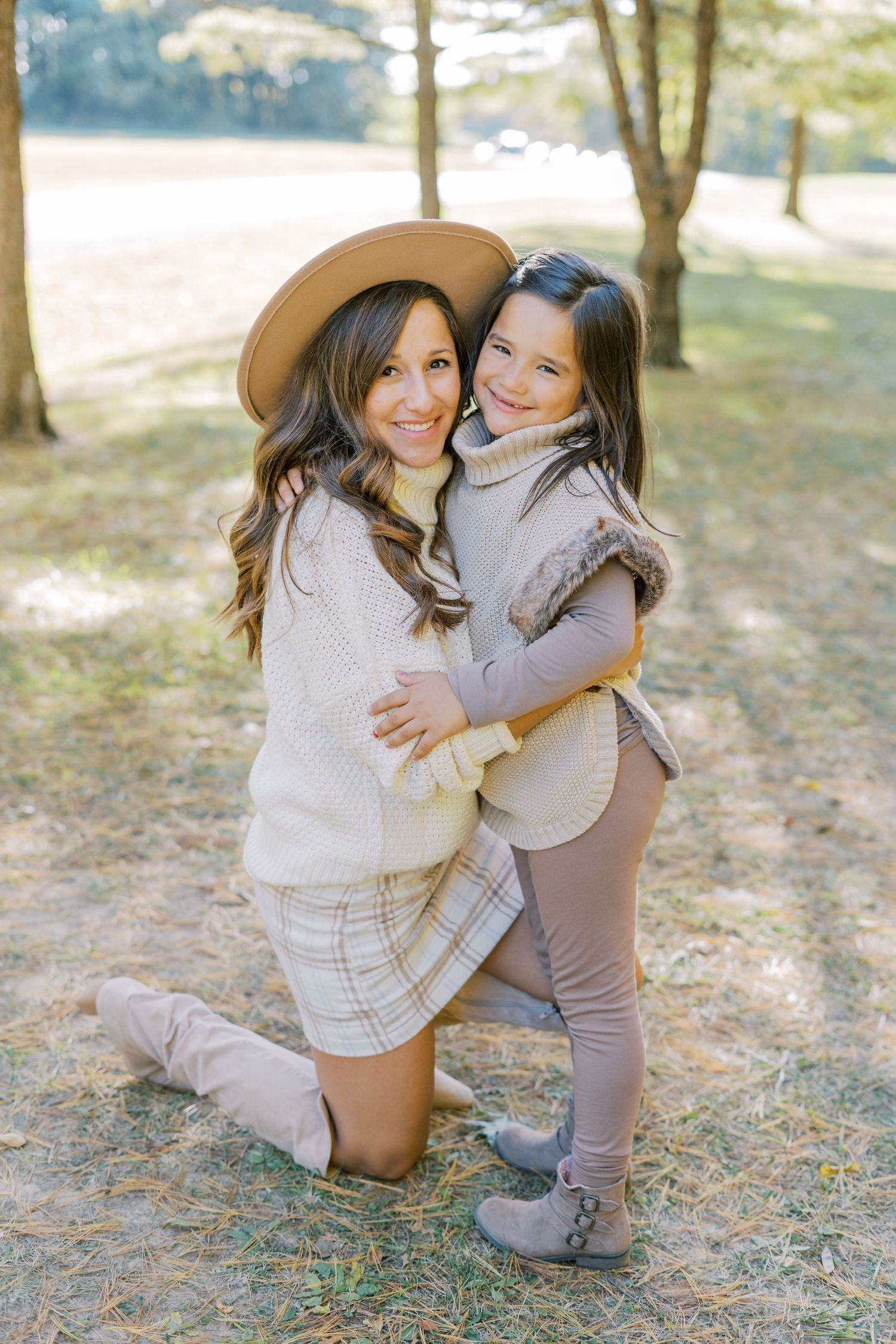 Mother and daughter in cozy sweaters sharing tender moment outdoors.