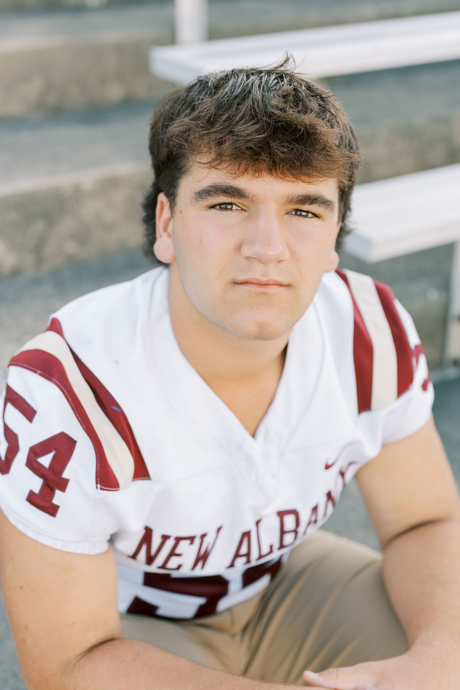 High school athlete poses in white and red New Albany football uniform in series of close-up portrait photos.