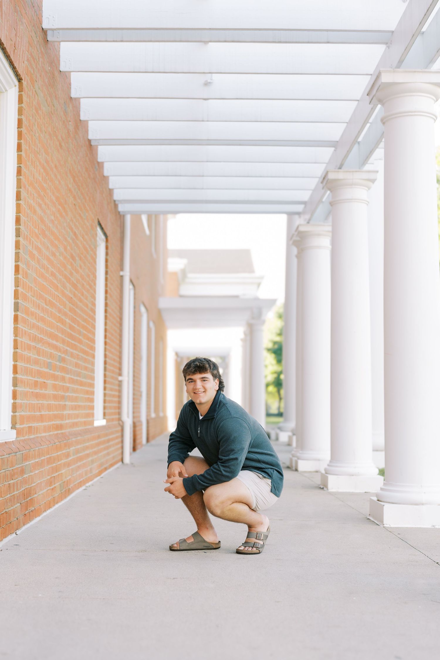 A sequence of four photos showing someone crouching and moving along a bright white colonnade hallway with brick walls.