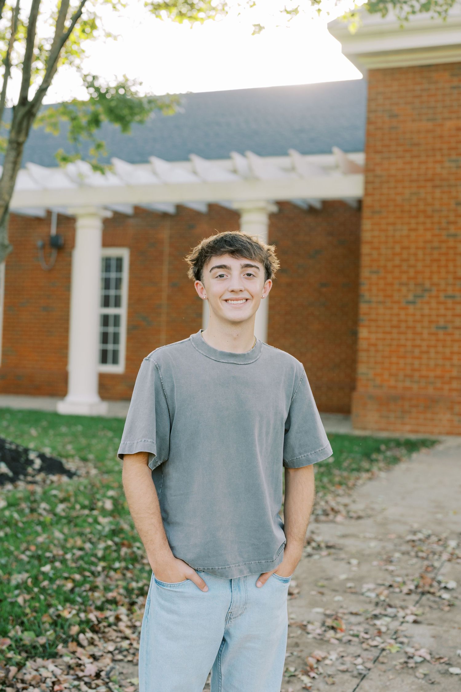 A casual outdoor photo series showing someone in a grey t-shirt and light jeans standing near a brick building.