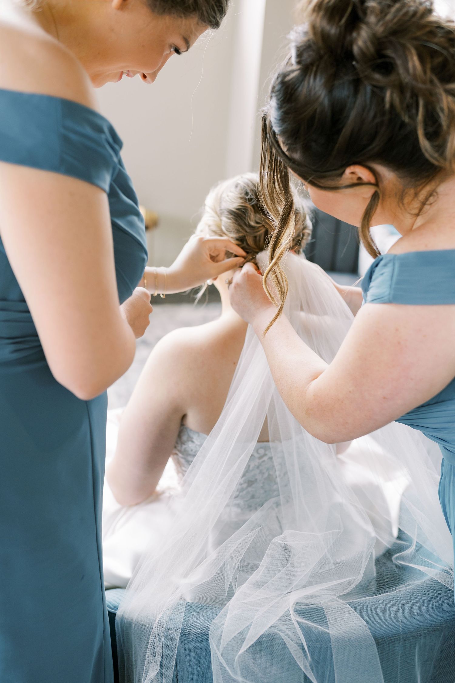 A row of bridesmaids in blue dresses stand next to a bride in a white tulle gown at a wedding ceremony.