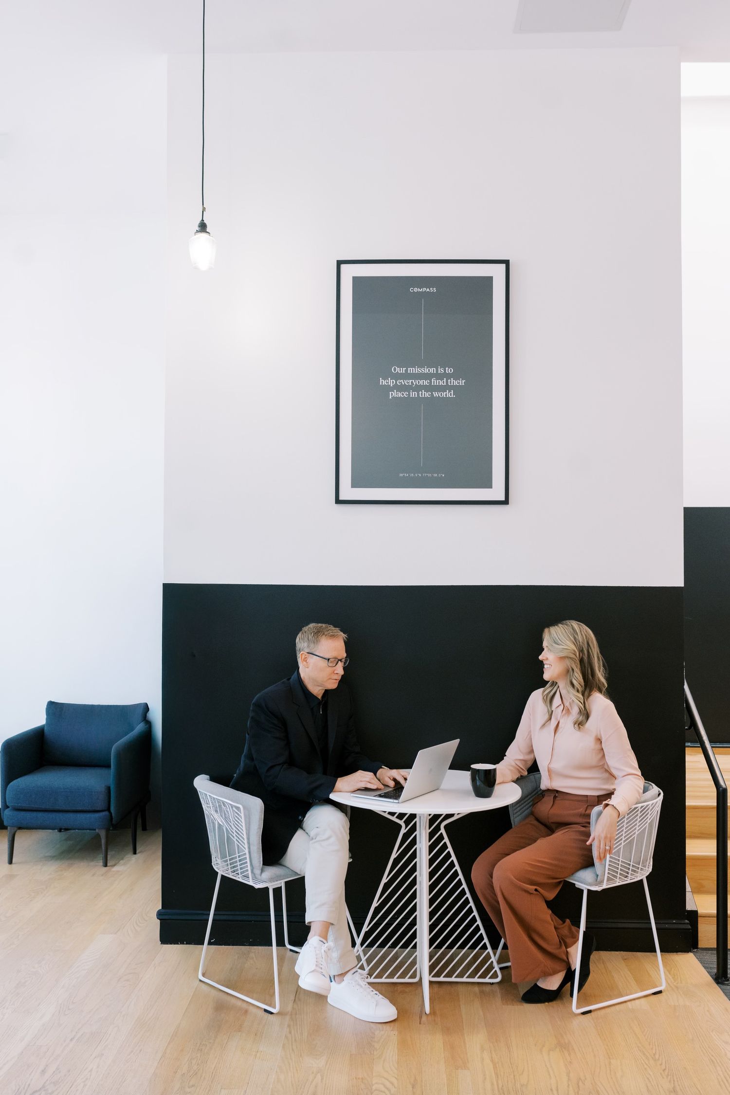 Modern office interior with black walls and blue accent chair showcasing minimalist design and collaborative workspace.