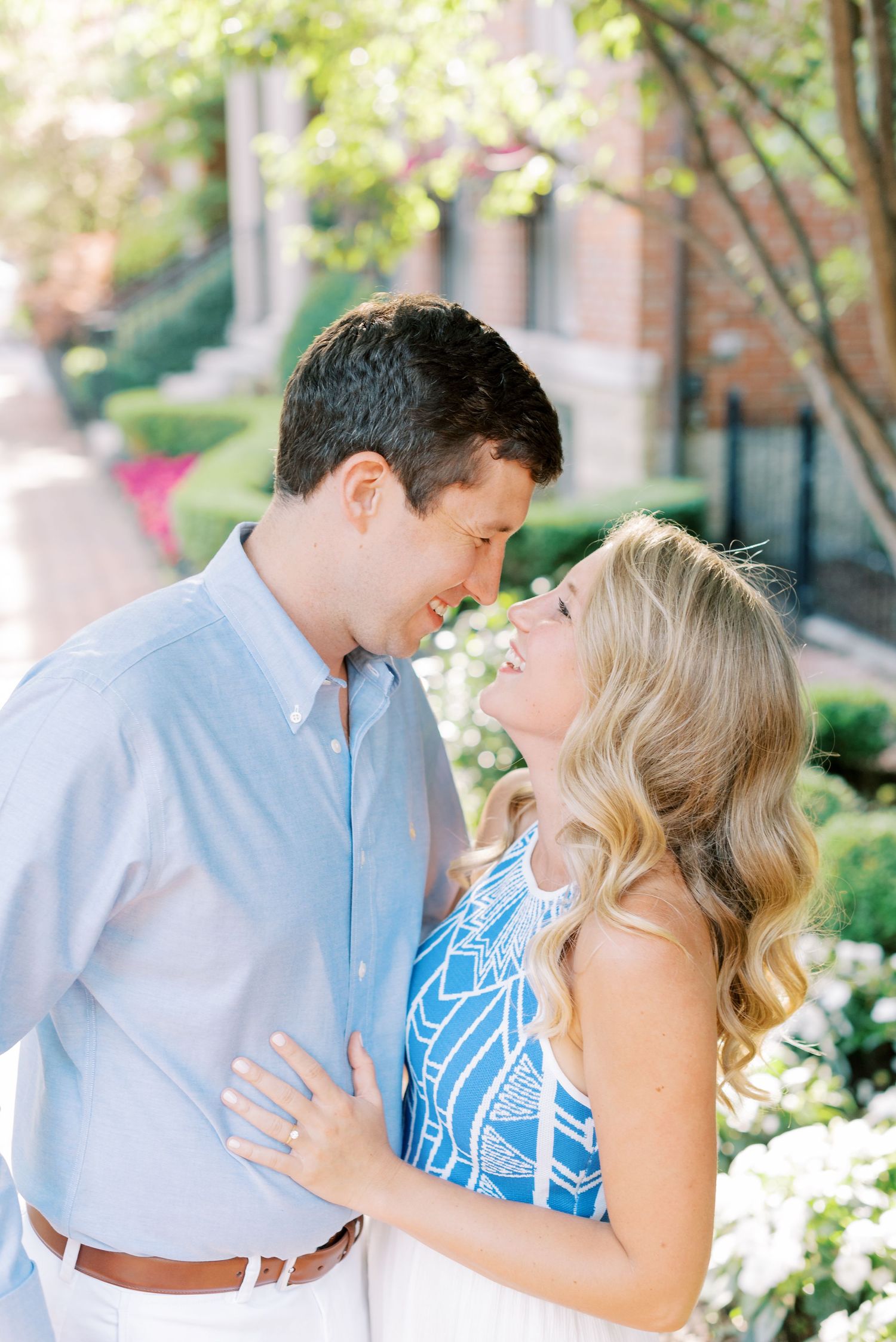 A couple in blue and white outfits share romantic moments in a garden setting with white flowers.