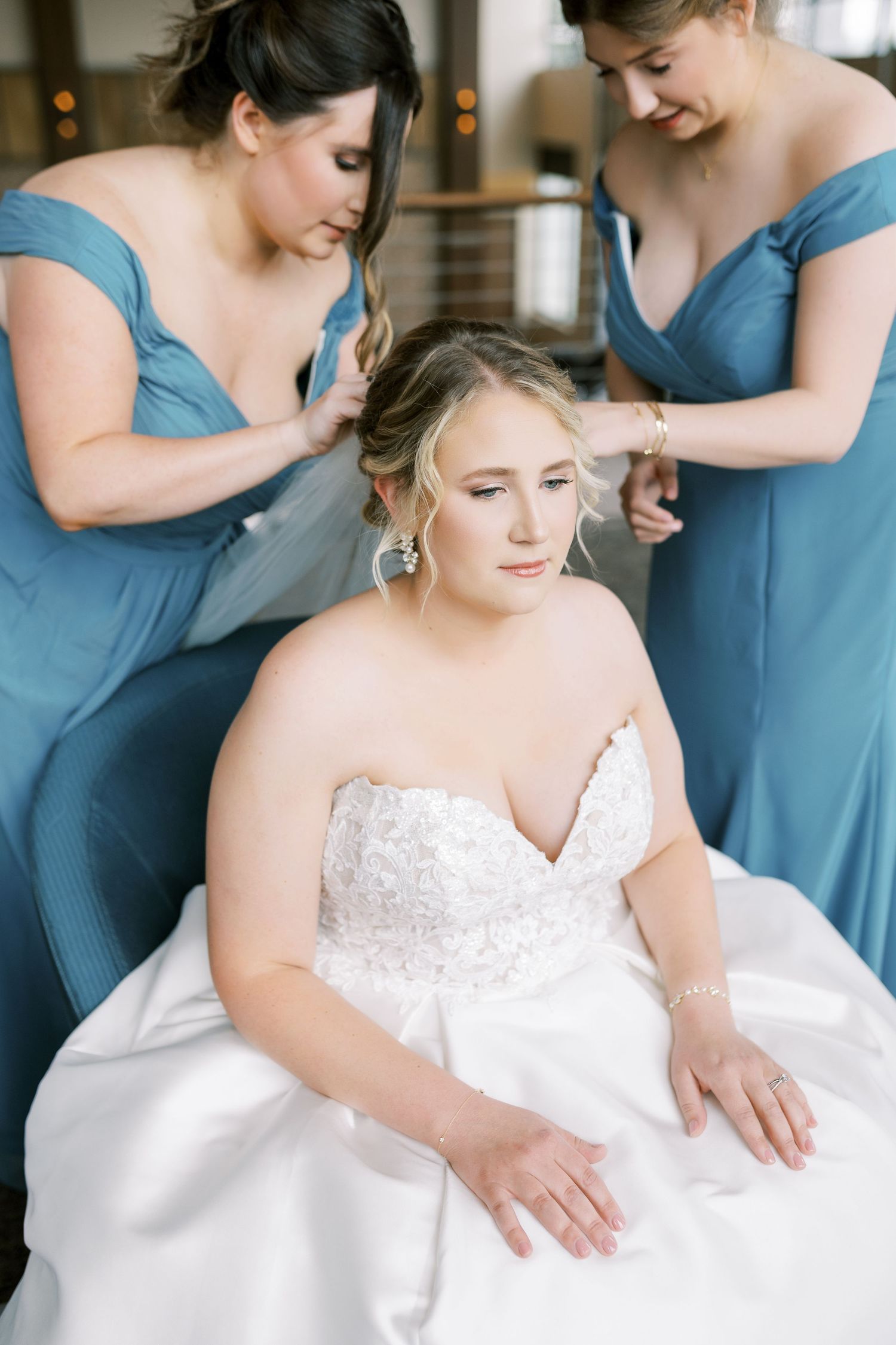 Bridesmaids in blue dresses help adjust a white wedding gown in a series of candid getting ready photos.