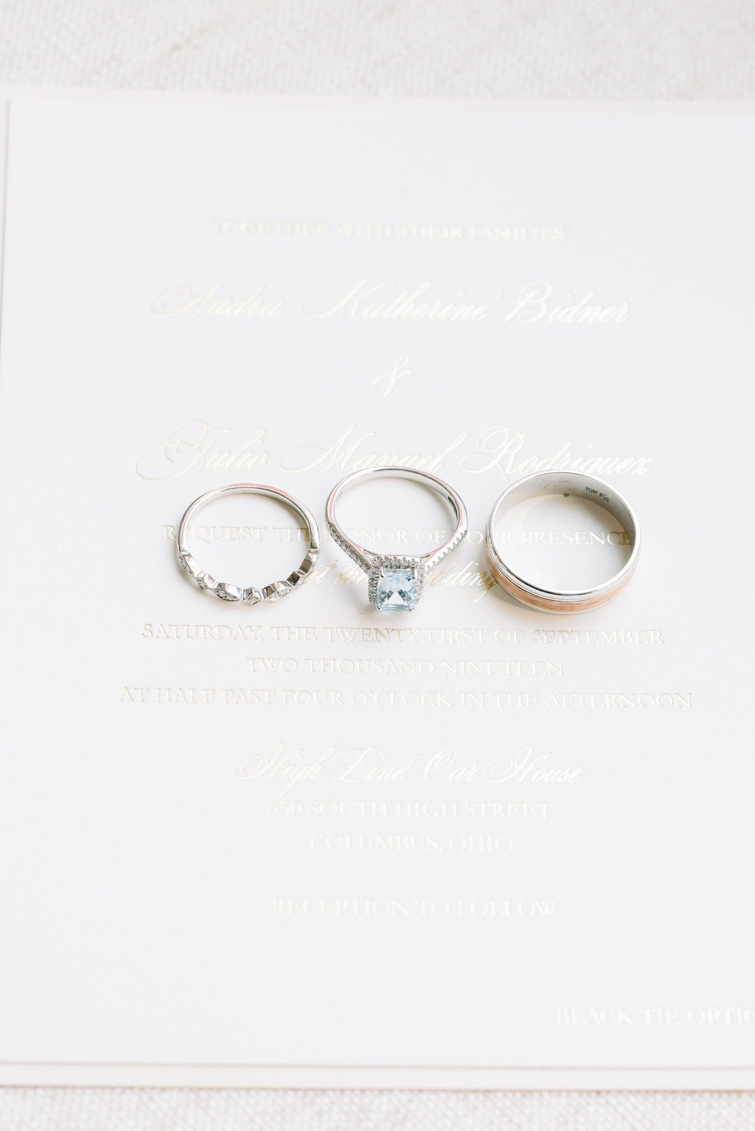 Three delicate silver rings including a solitaire engagement ring with a square blue gemstone displayed on white background.