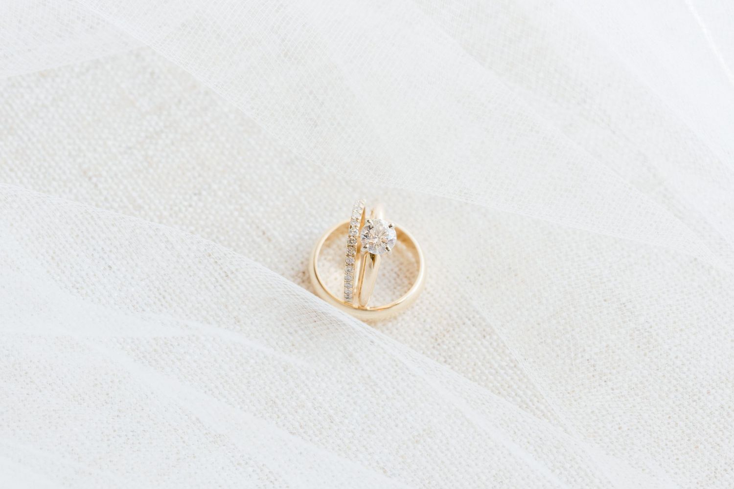 Minimalist gold wedding rings on white textured background.