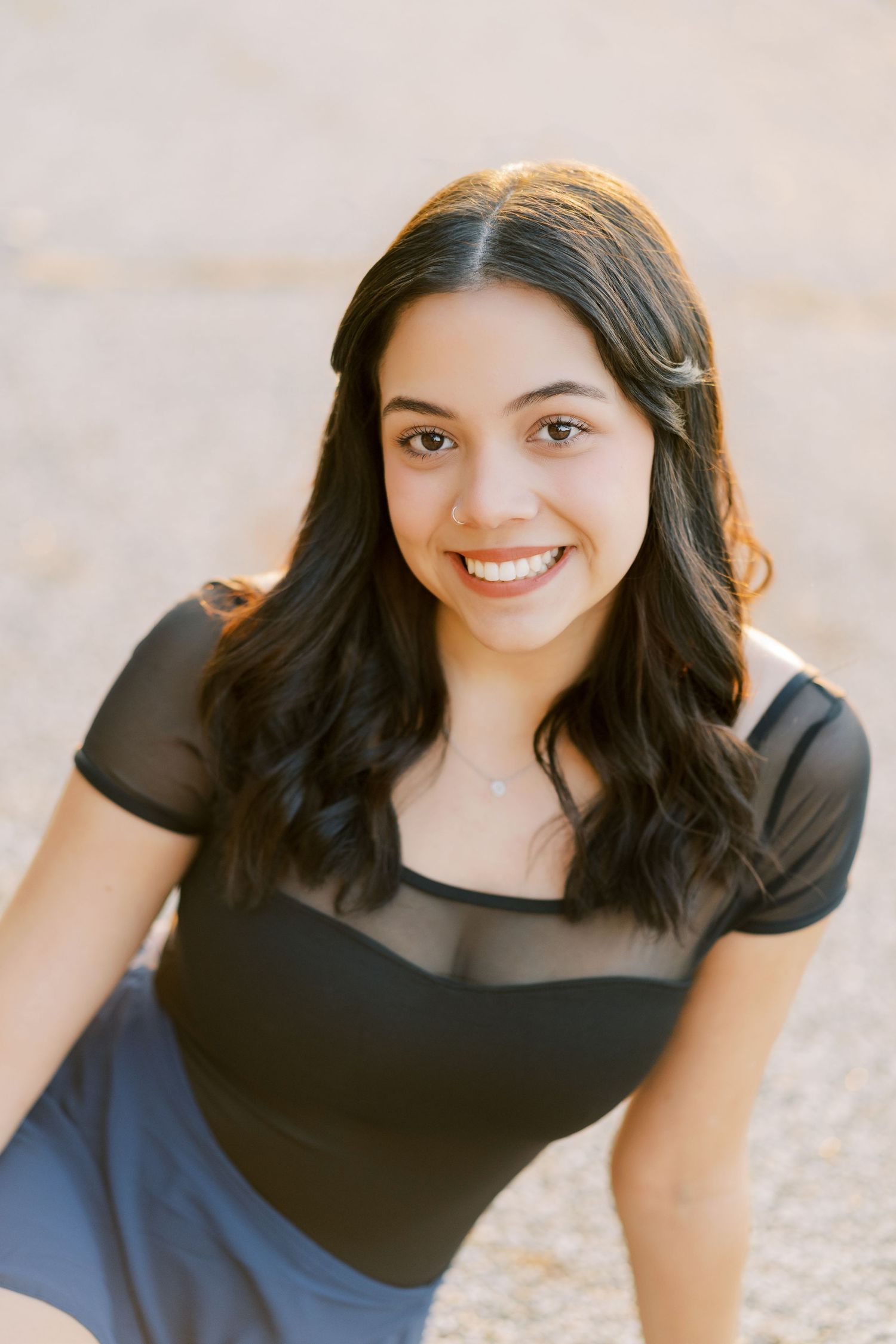 Portrait of someone in a black top against a light background with soft lighting.