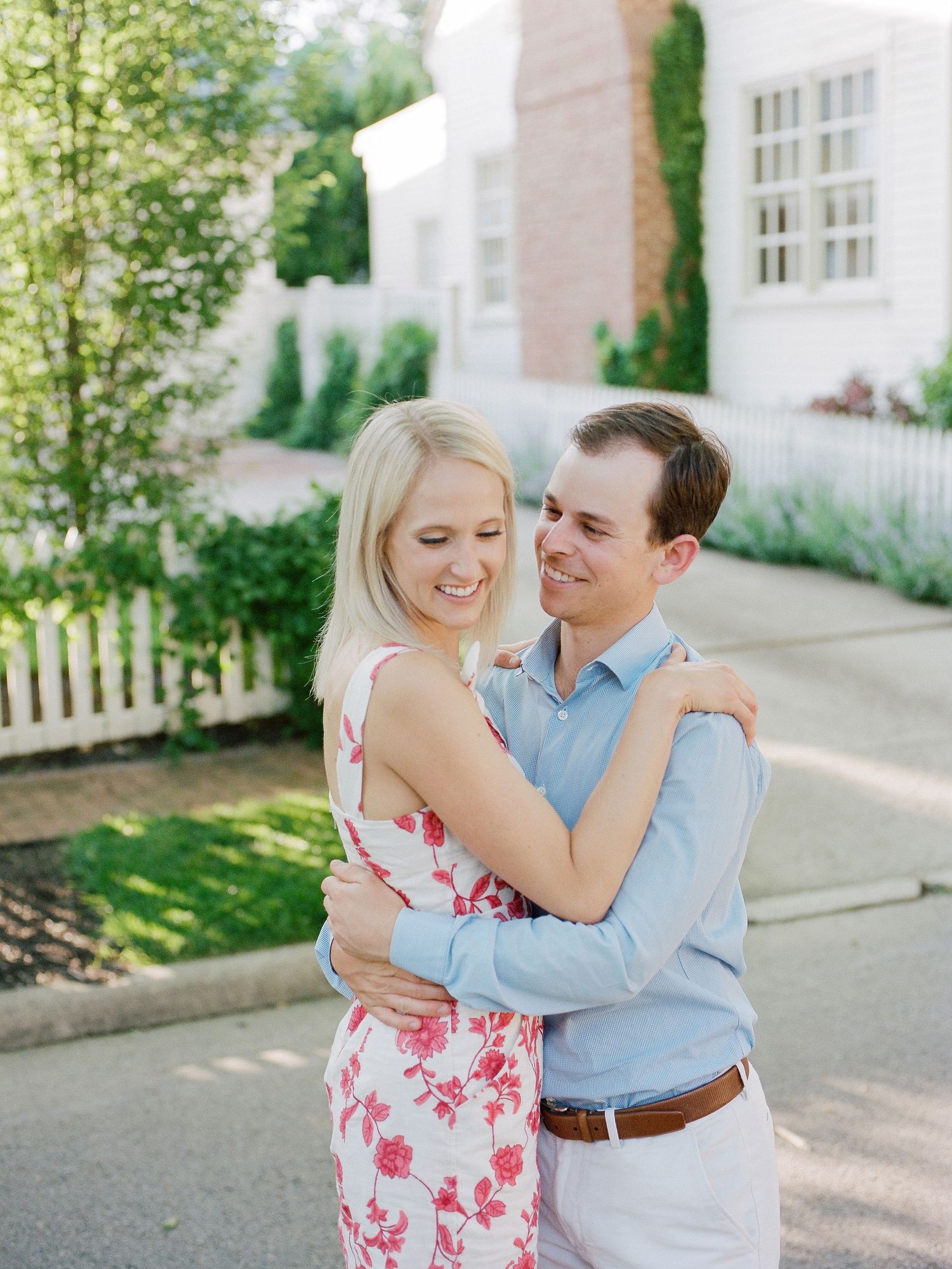 A couple shares a romantic moment dancing together in a garden setting on a sunny day.