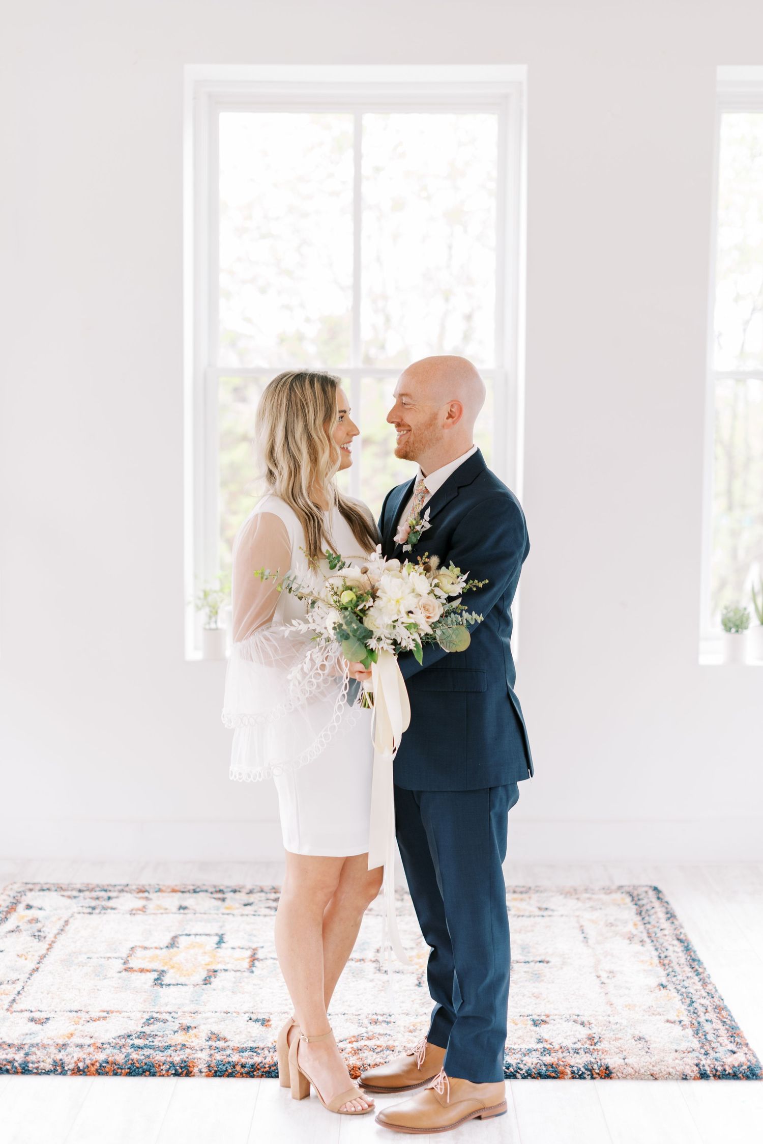 A romantic moment captured in a bright white room with decorative rugs.