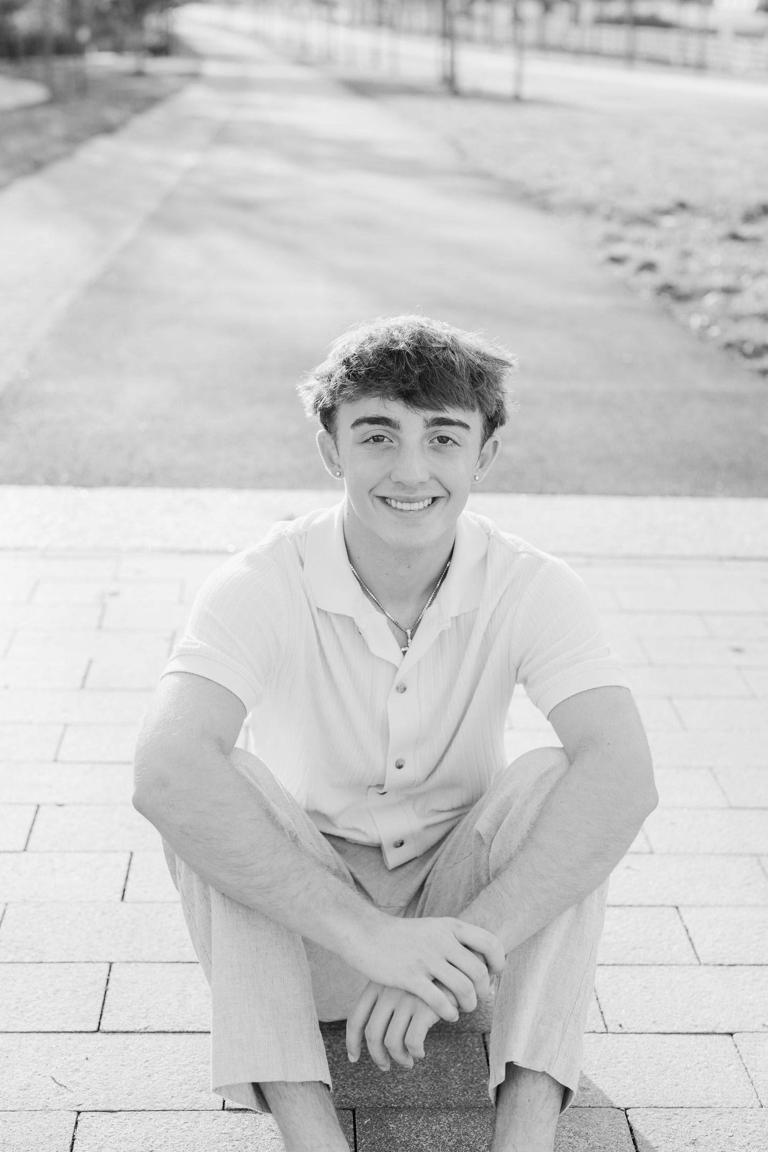 A series of black and white portraits showing someone in casual attire sitting on stone steps outdoors.