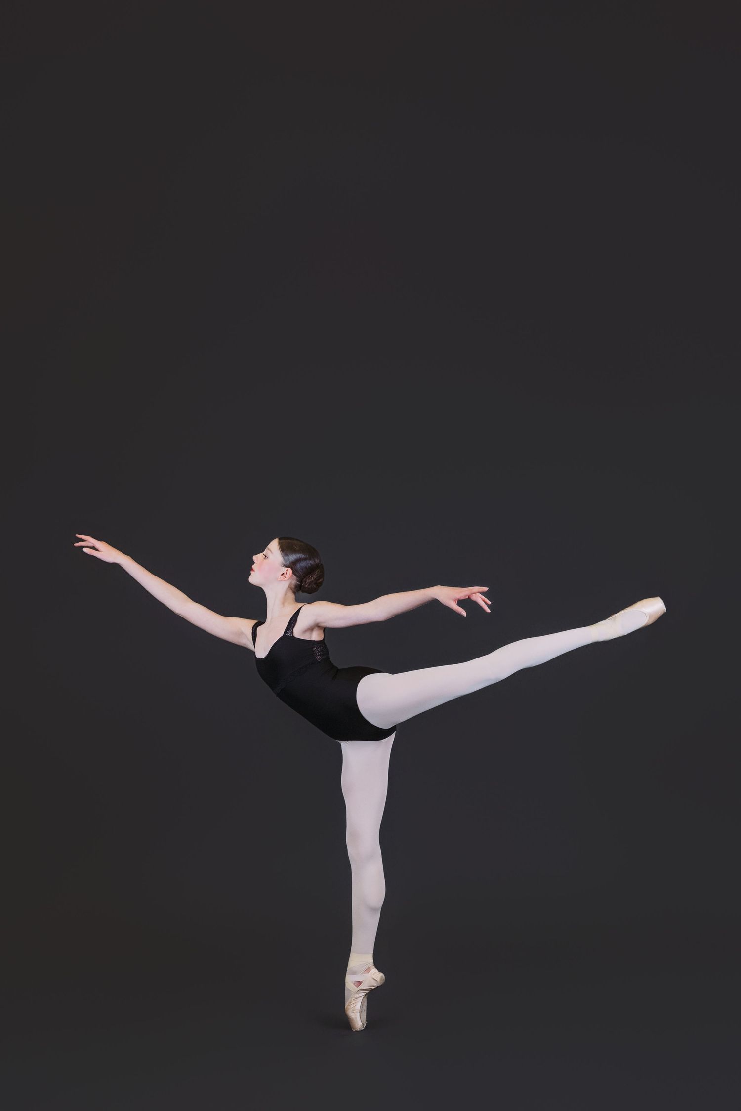 Ballet dancer in black leotard performs graceful arabesque sequence against dark background showing four dynamic poses.