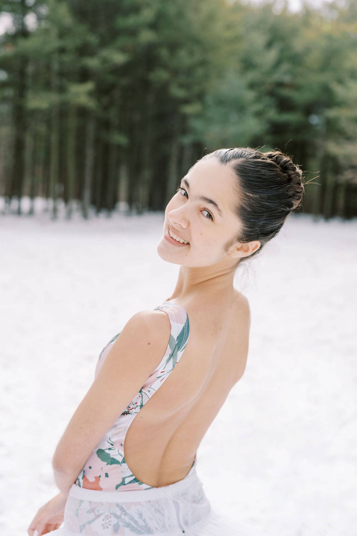 A person in a white dress poses joyfully against a snowy winter forest backdrop in a series of candid shots.