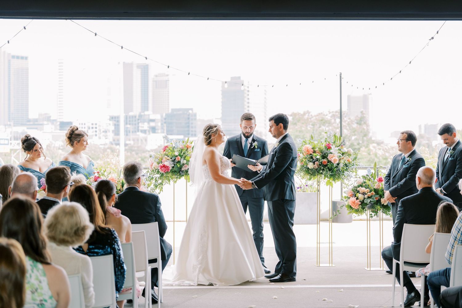 A panoramic collage of an elegant rooftop wedding ceremony with city skyline views and white floral arrangements.