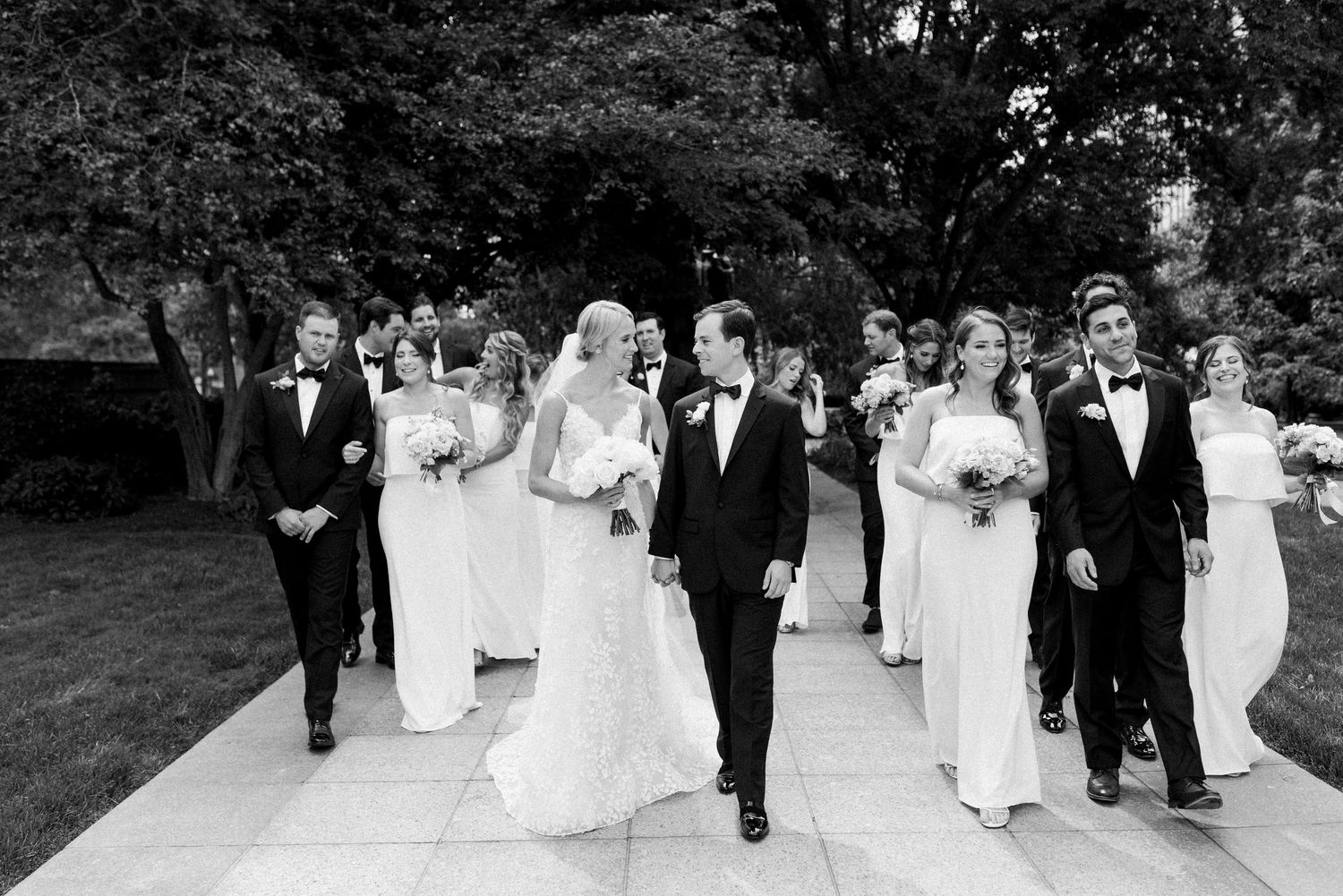 Wedding party walking in formal procession outdoors in black and white.