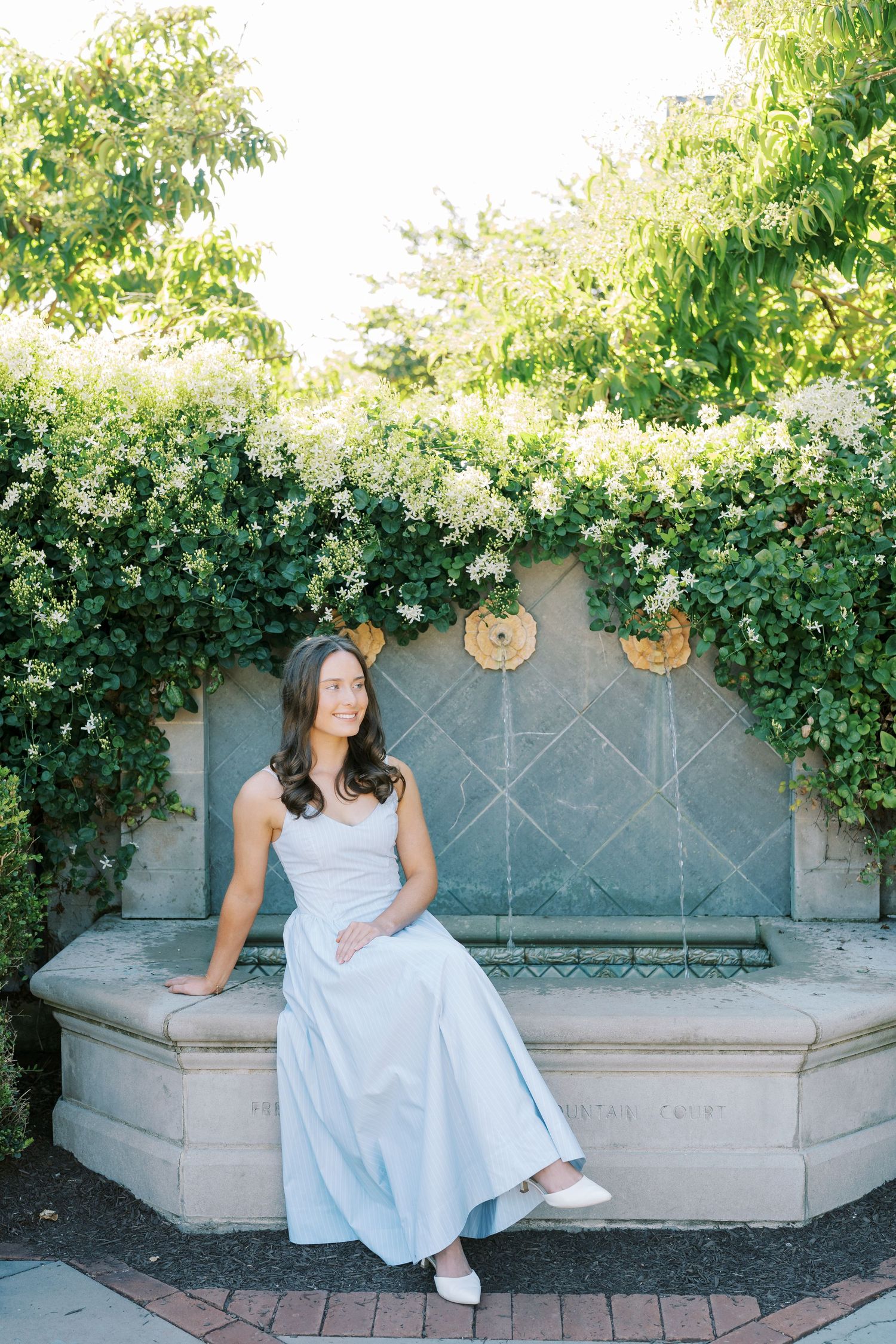 A sequence of four photos showing someone in a light blue dress sitting on a stone bench against a garden wall with greenery.
