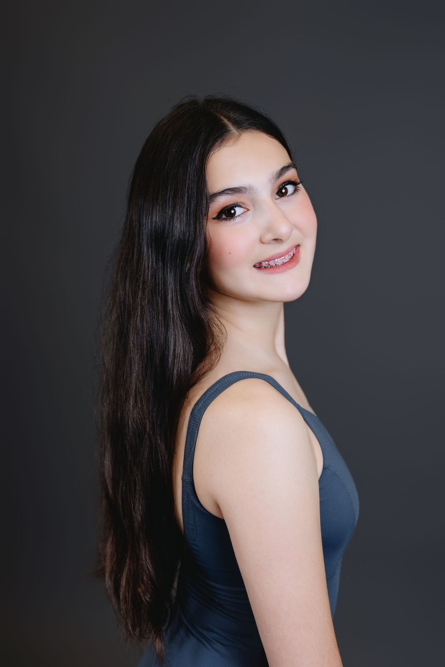 Studio portrait series showing a person with long dark hair in a navy sleeveless top against a dark background.