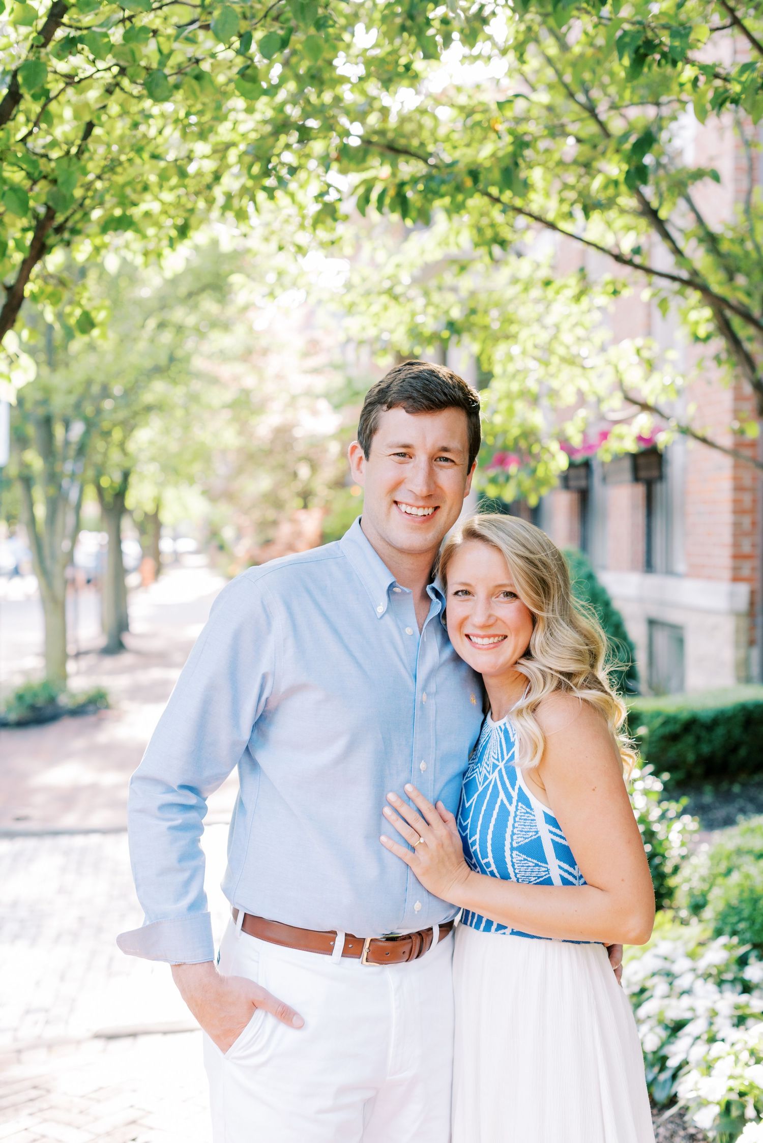 A couple in coordinated blue and white outfits pose together in a garden setting during an outdoor photoshoot.