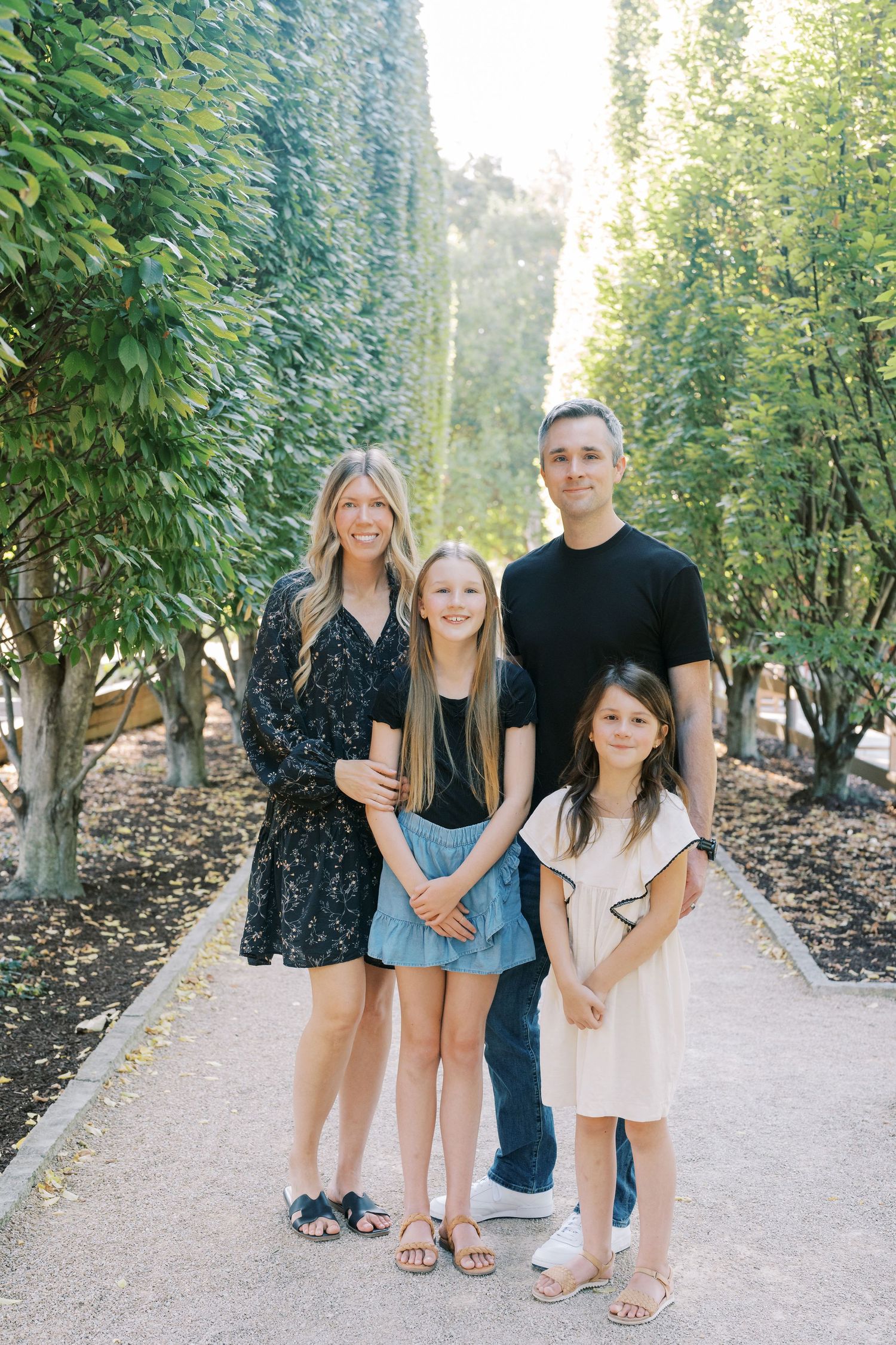 Family portrait session on stone path surrounded by lush greenery.