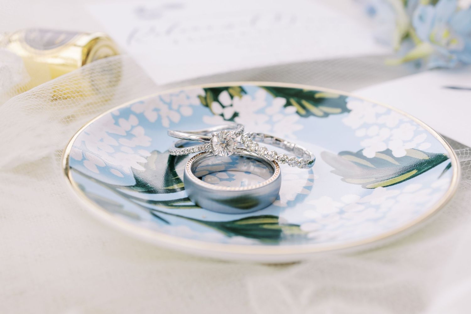 Wedding rings displayed on a decorative floral plate with blue and white pattern details.